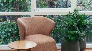 Heller ruhiger Therapieraum mit Sessel, Beistelltisch und Pflanzen vor großem Fenster