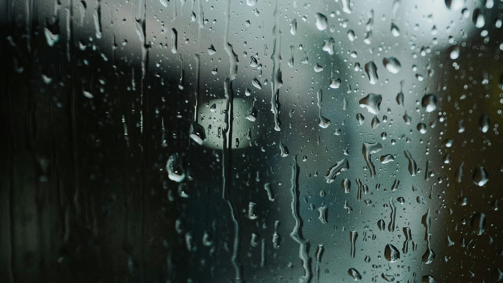 Regentropfen laufen über eine Fensterscheibe und erzeugen eine stille, nachdenkliche Stimmung.